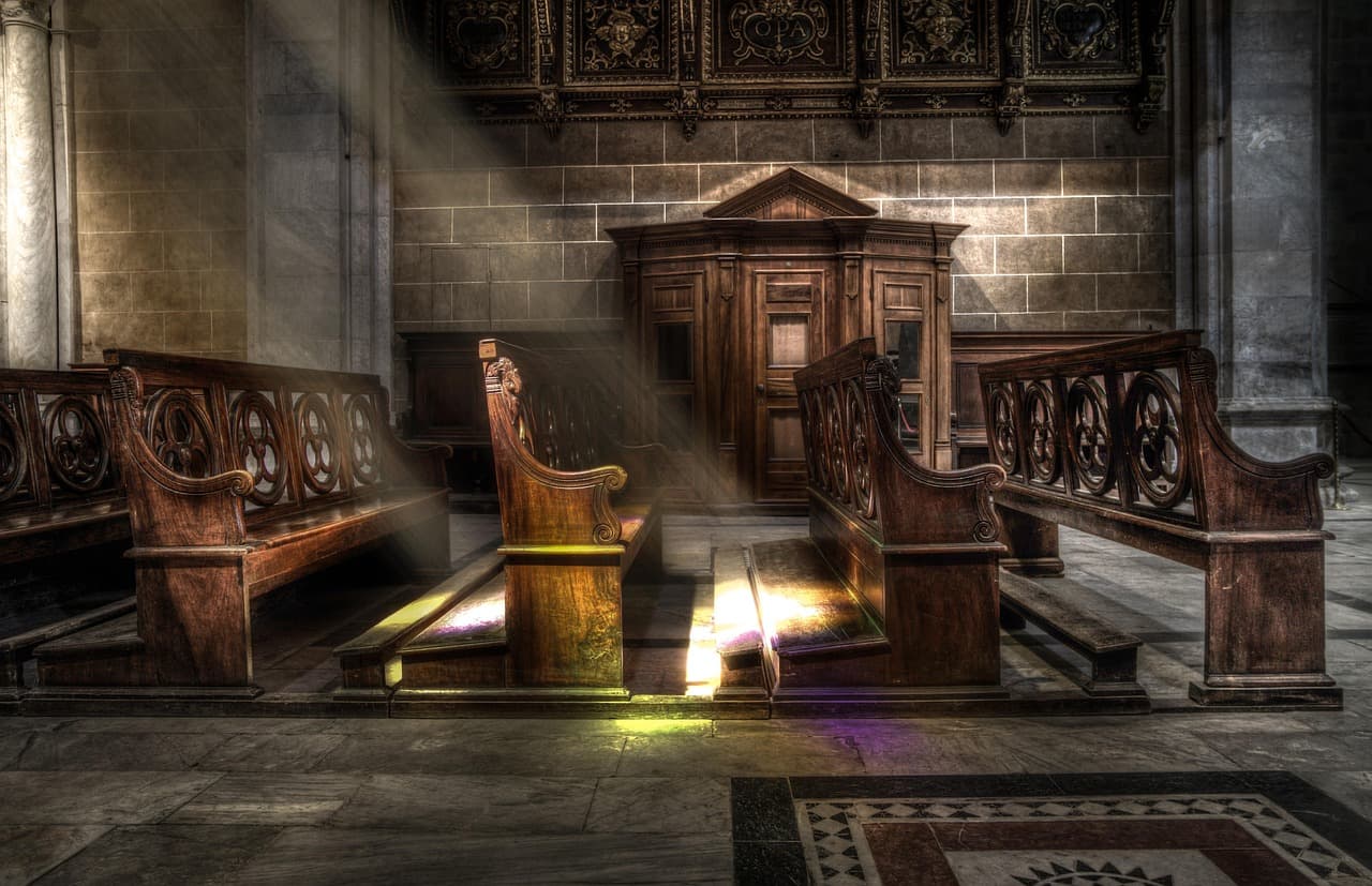Sunlight falling across empty wooden pews in a quiet sanctuary, waiting for a word.